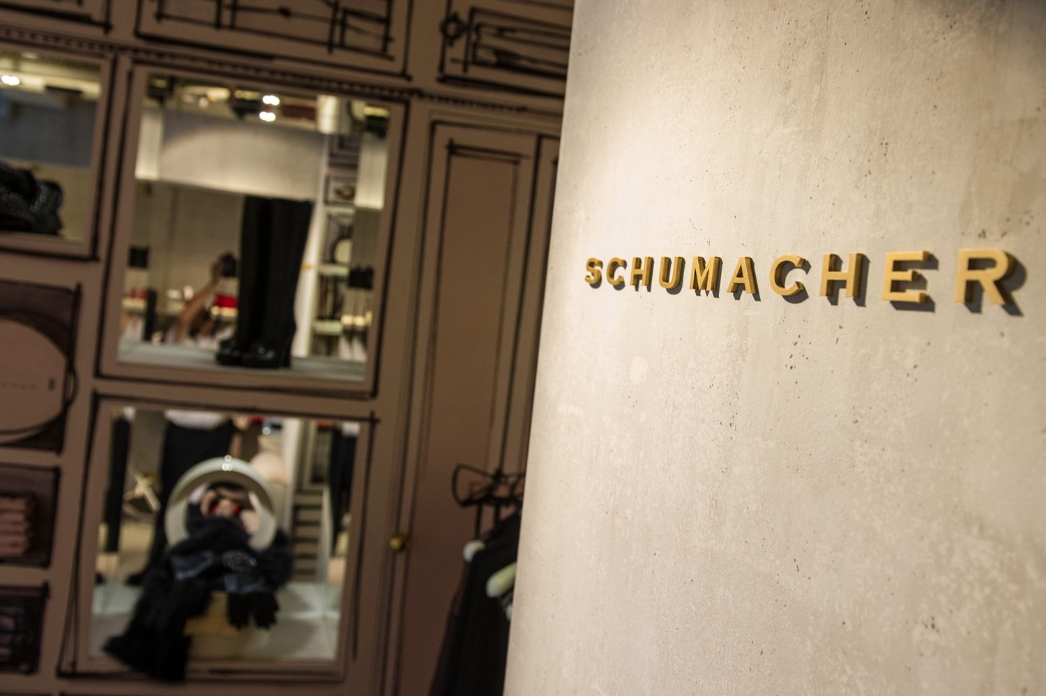 Close-up of Schumacher signage on a textured wall with reflective surfaces.