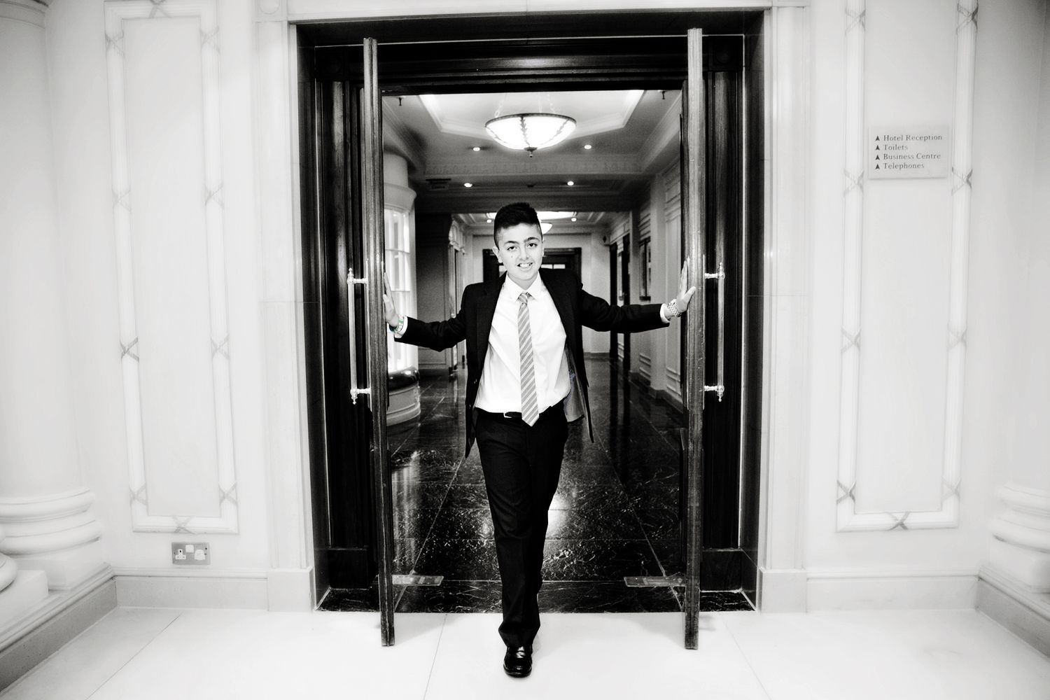 A black and white photo series showing a person walking through an elegant hallway with ornate architectural details.