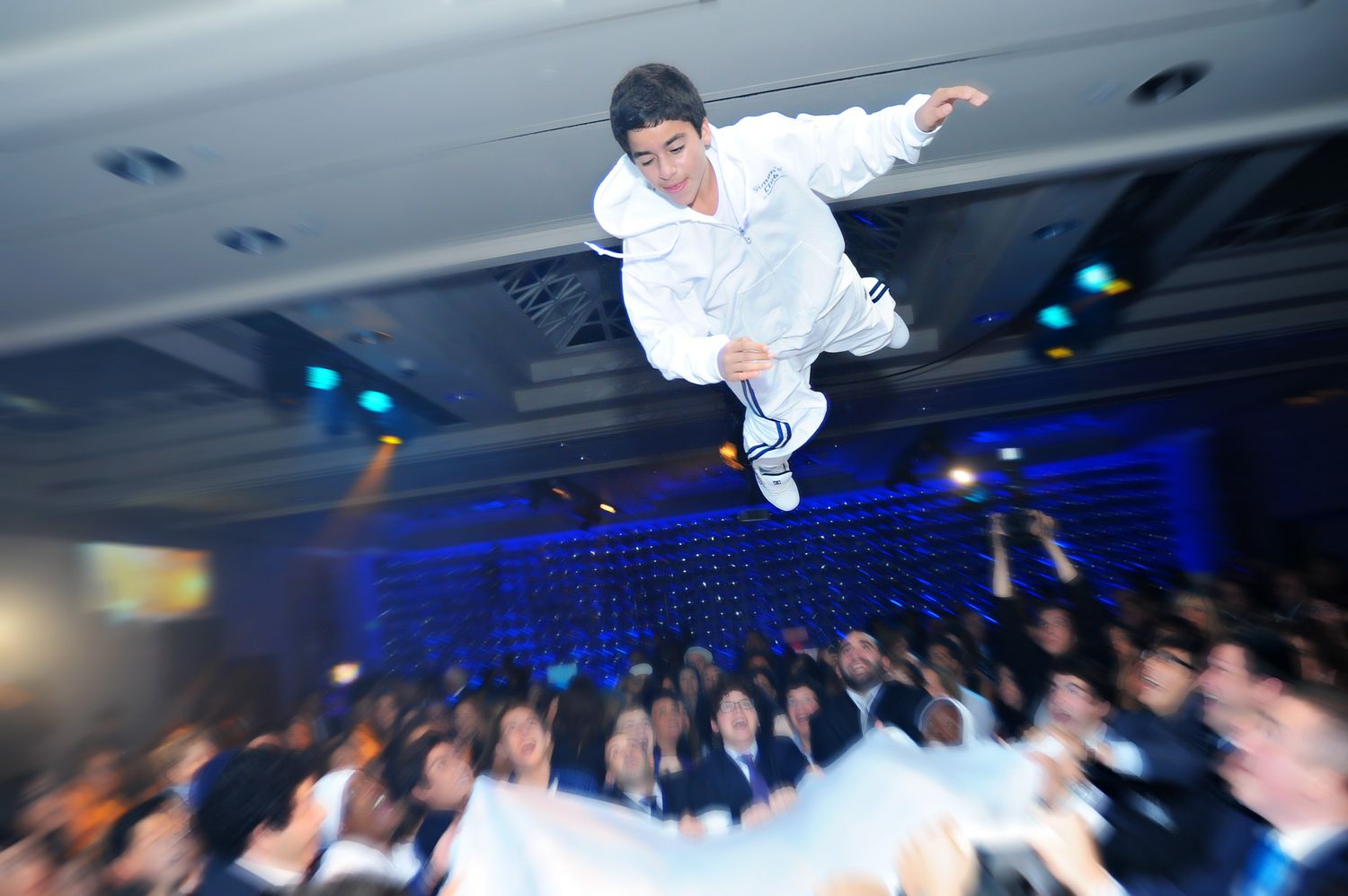 A person performing a high-energy backflip on a dance floor with blue lighting in the background.