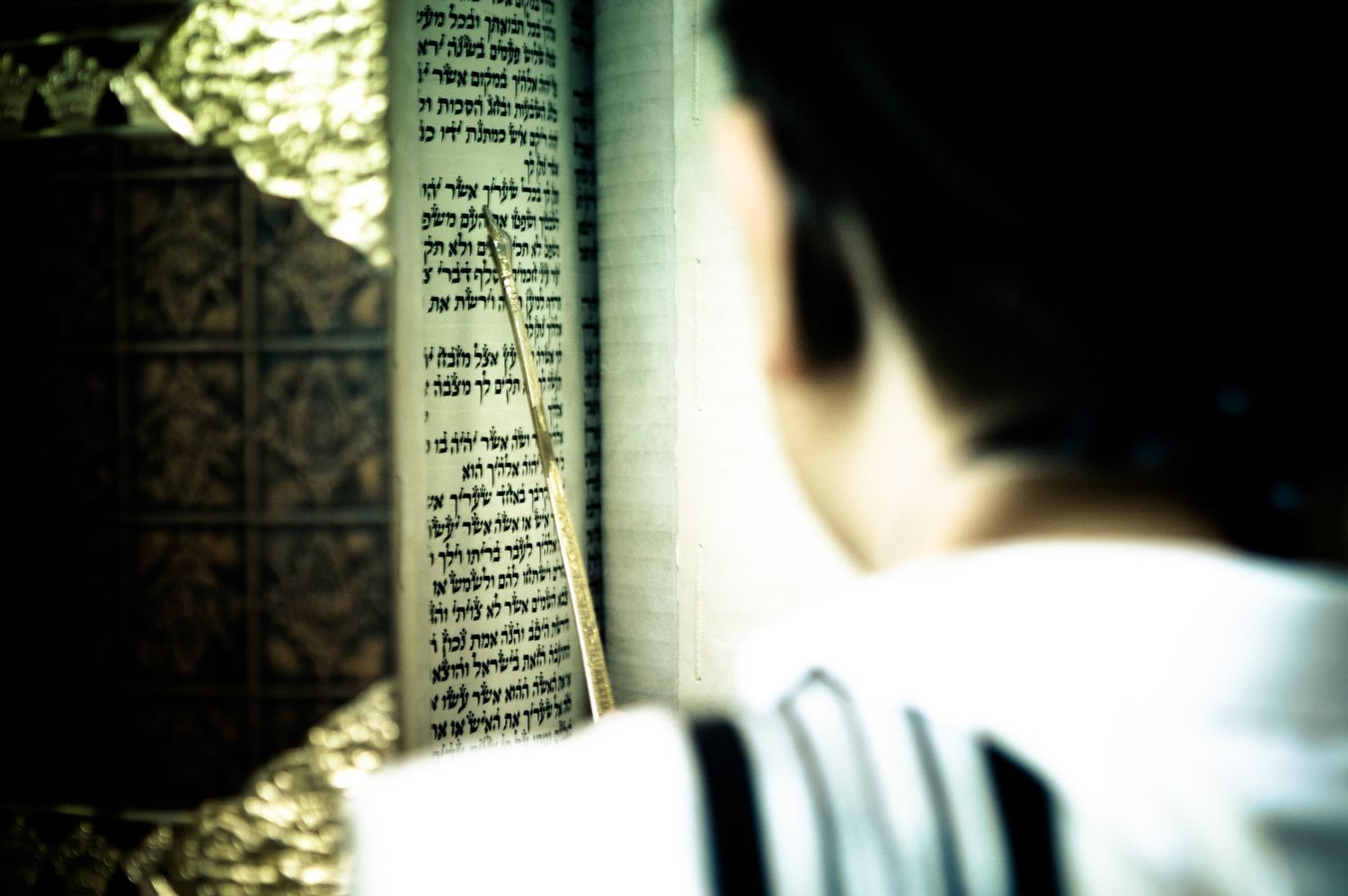 Close-up view of ancient Hebrew text on weathered parchment pages illuminated by natural light.