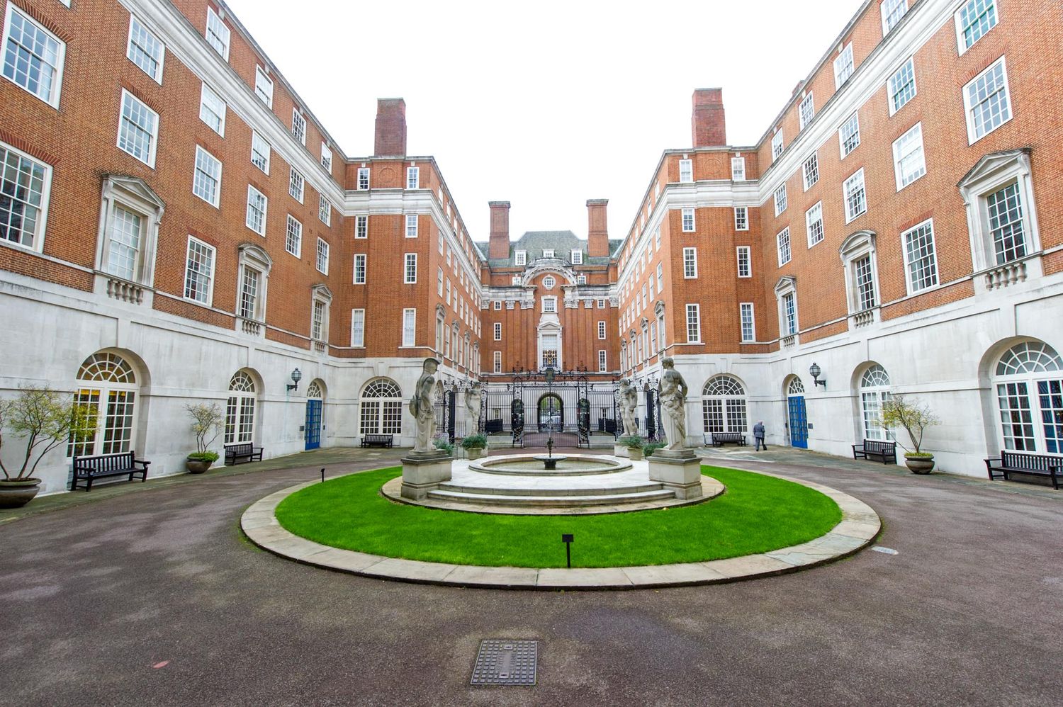 Elegant brick courtyard with circular driveway and Georgian architecture at an upscale venue.