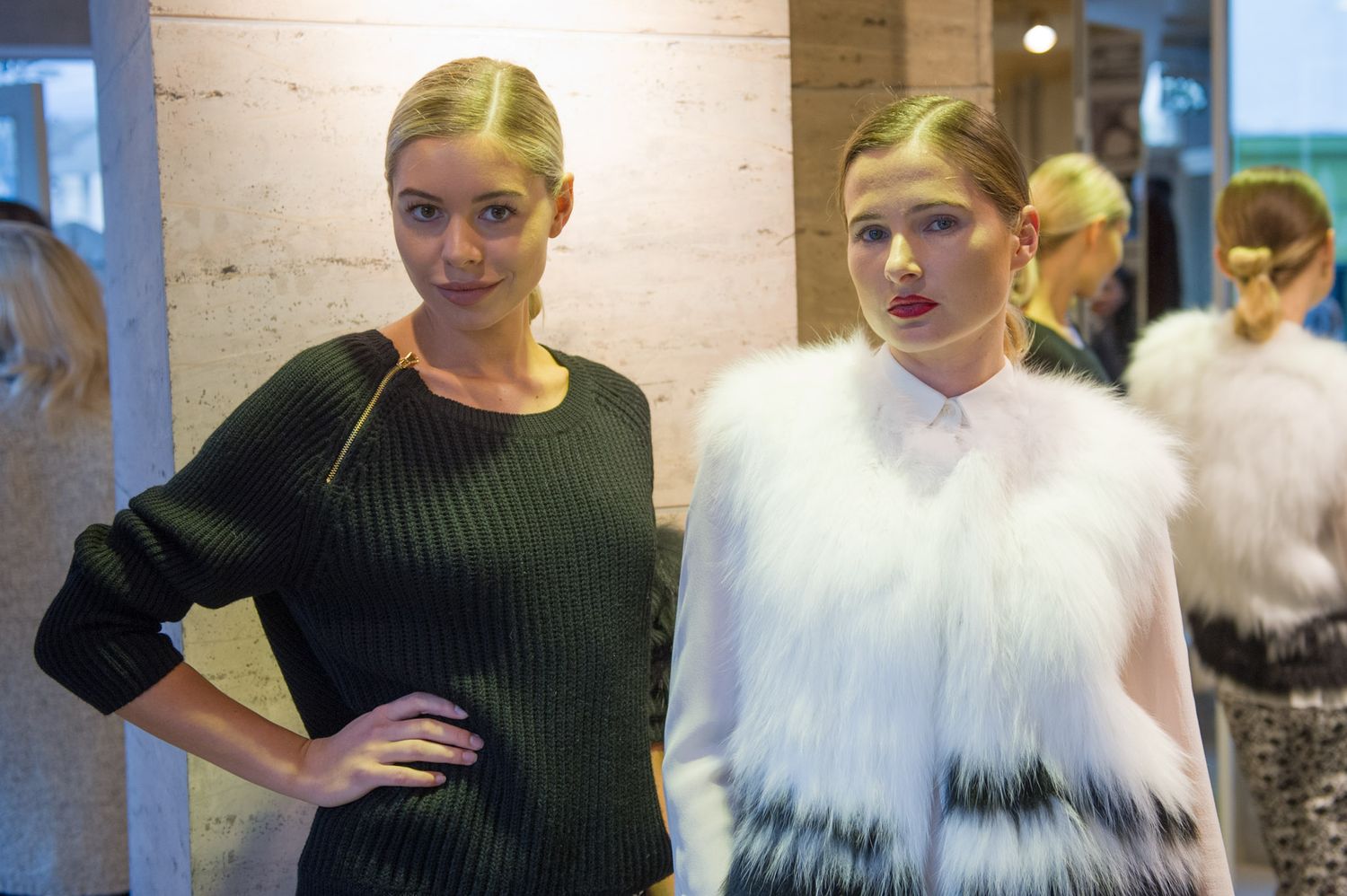 Fashion models posing in winter outfits including white fur and black sweaters.