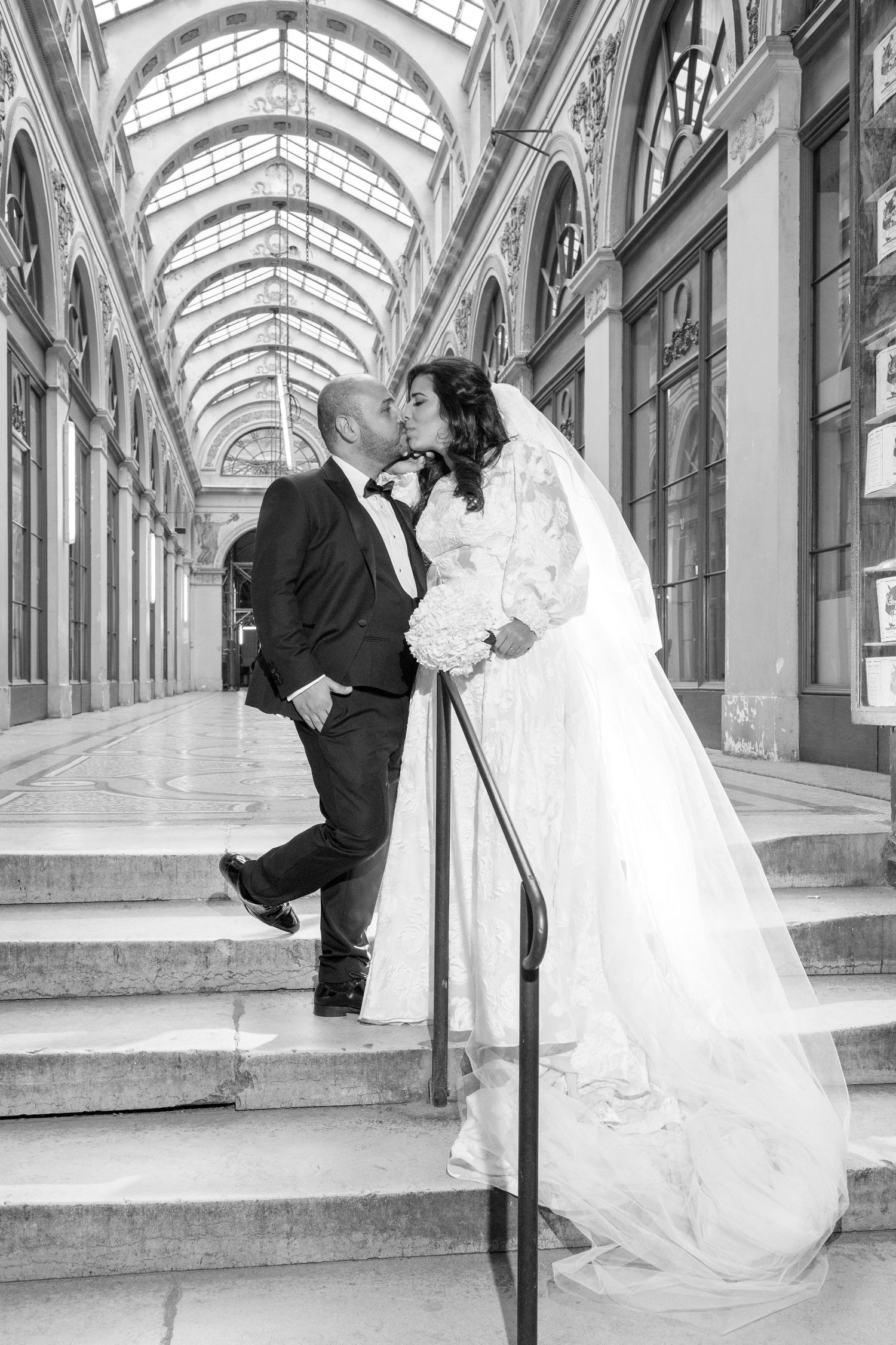 A black and white photo series showing a romantic wedding couple posing in a grand arched hallway with natural lighting.