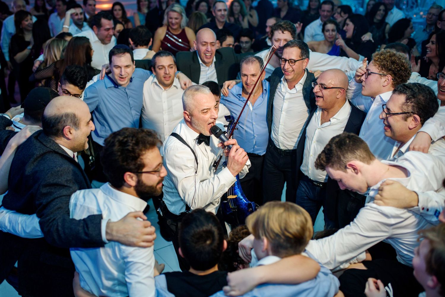 A crowded dance floor filled with people celebrating and dancing at what appears to be a wedding reception.