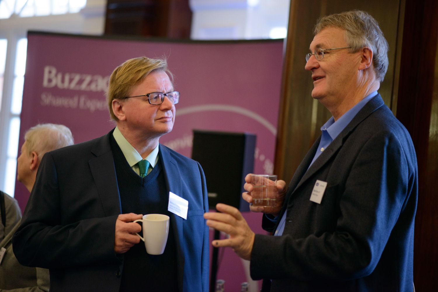 Two attendees having a conversation while holding coffee cups at a business networking event.