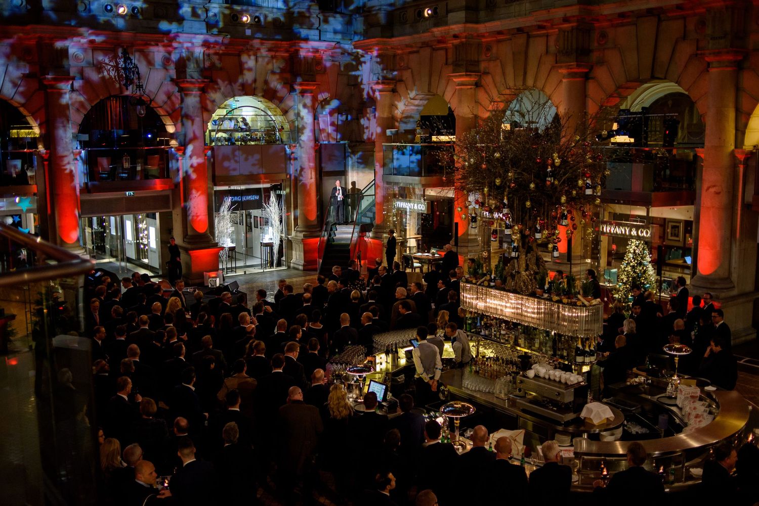 Elegant evening event venue with dramatic red lighting and classical architectural columns.