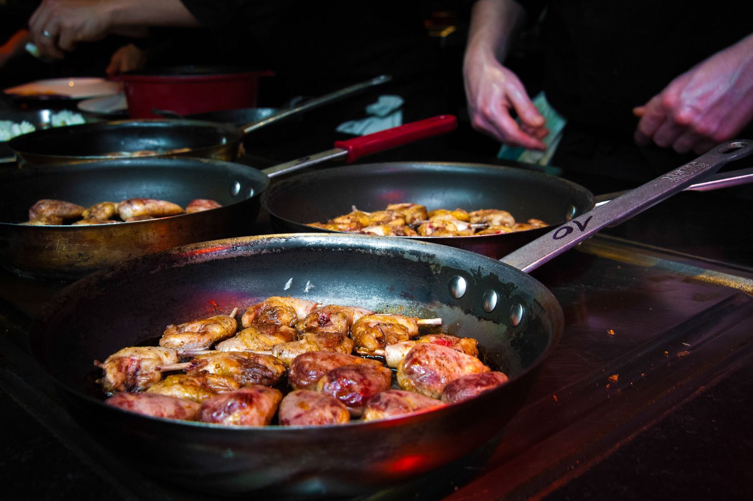 Close-up shots of sizzling food being prepared in pans with dramatic lighting.
