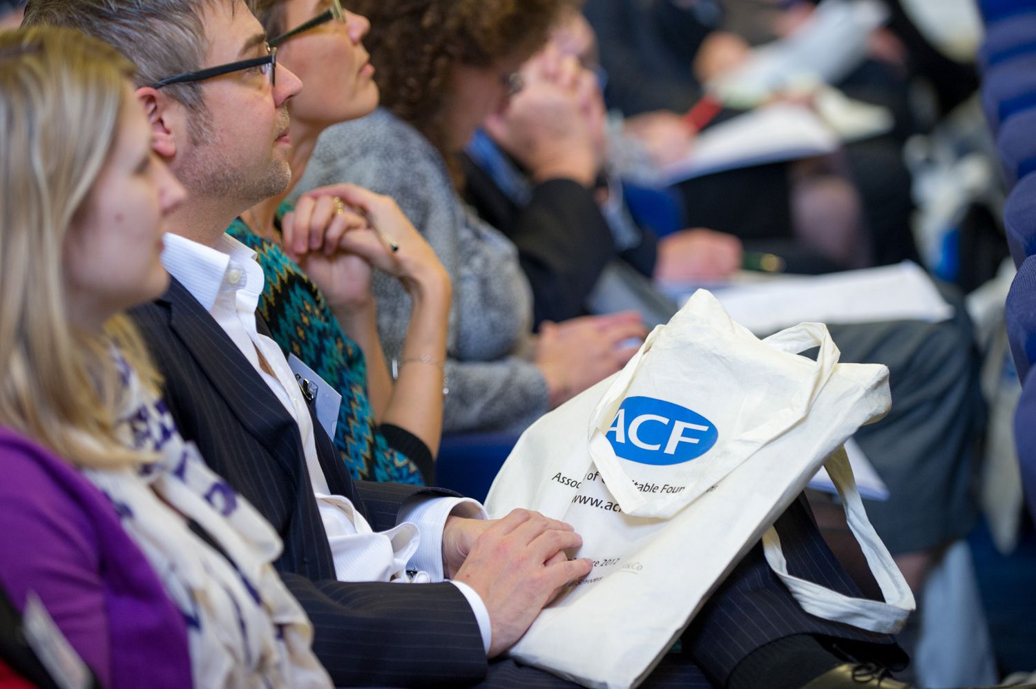 Business conference attendees taking notes during a presentation.