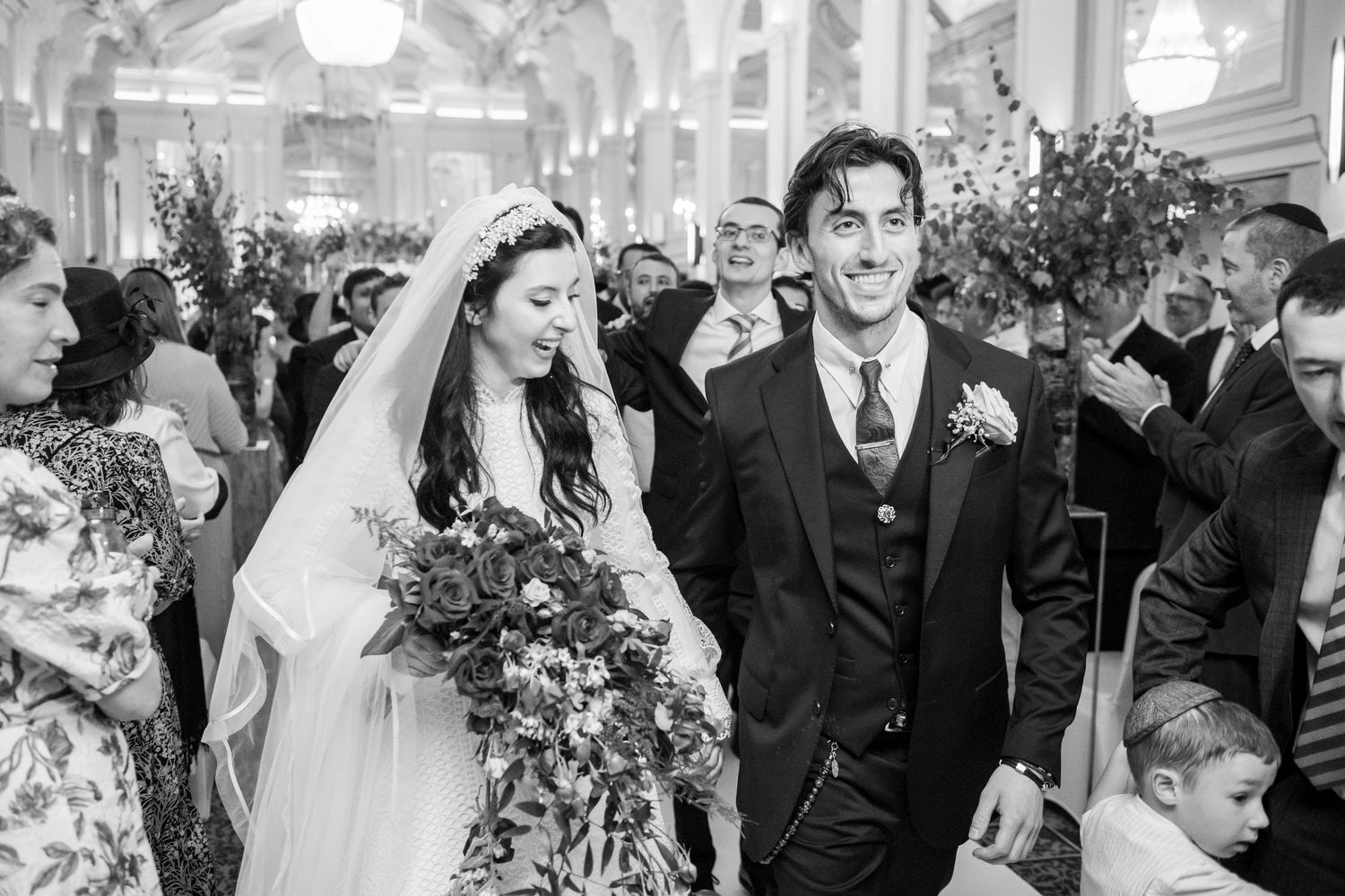 Wedding party members celebrate and dance together during a joyous reception at an elegant indoor venue.