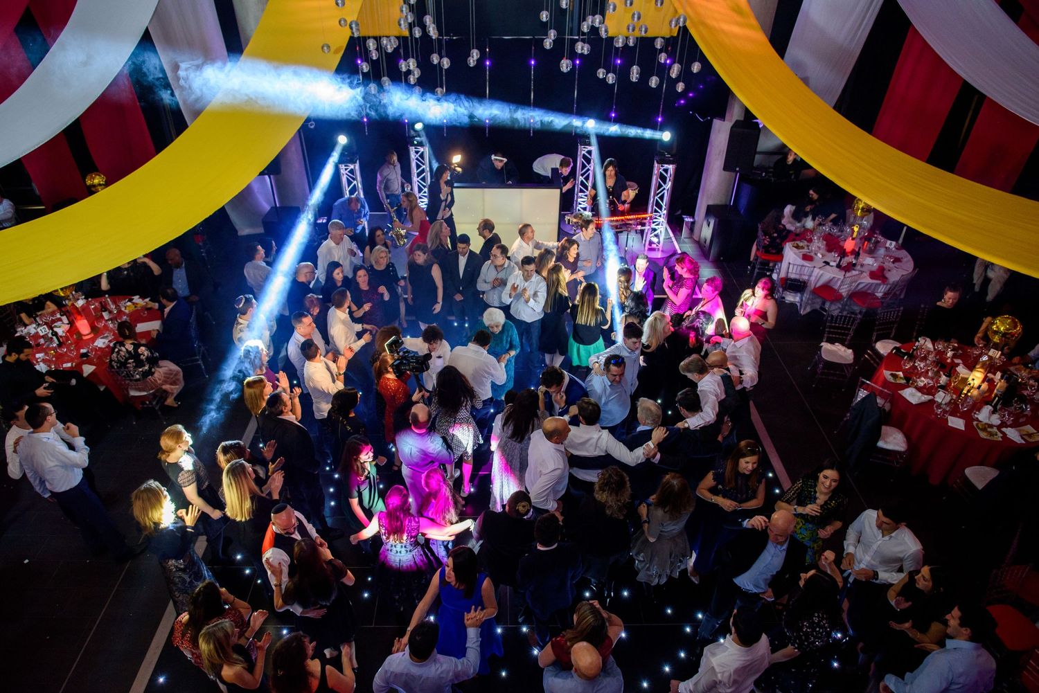 Crowded nightclub with colorful lighting and people dancing on a packed dance floor during a lively party.