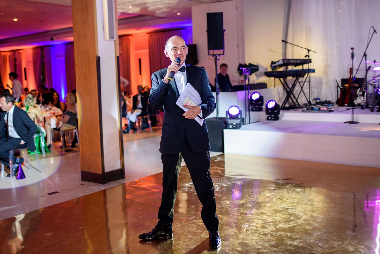 Large event space with dance floor illuminated by colorful lighting and audio equipment.