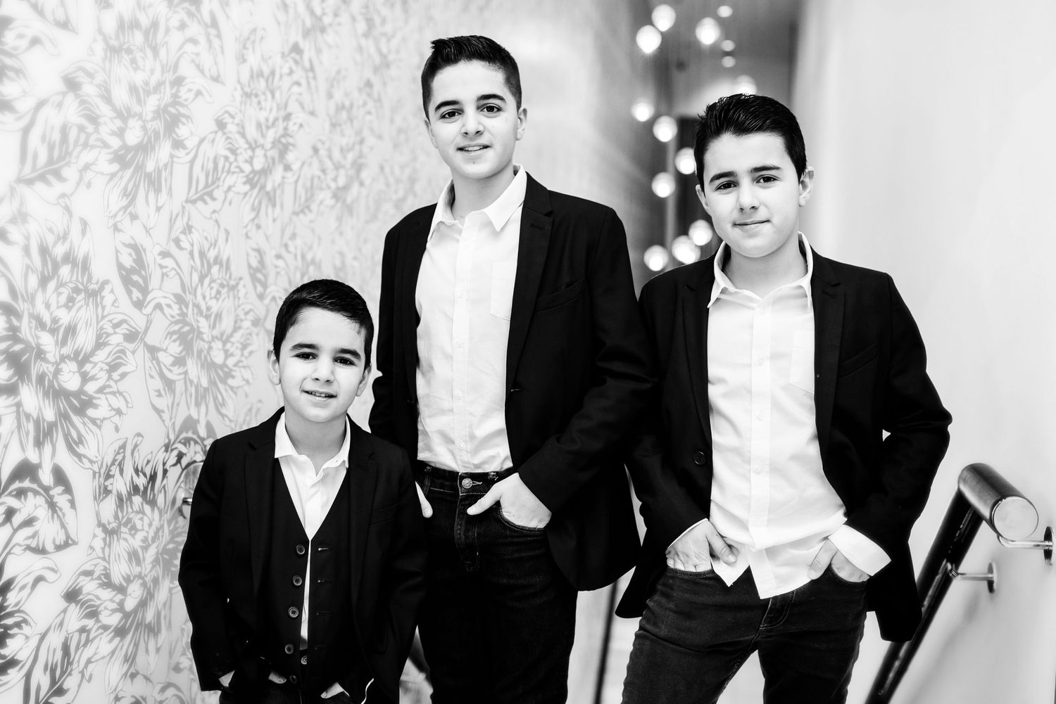 Black and white photo of a group in formal attire posing together against a light background.