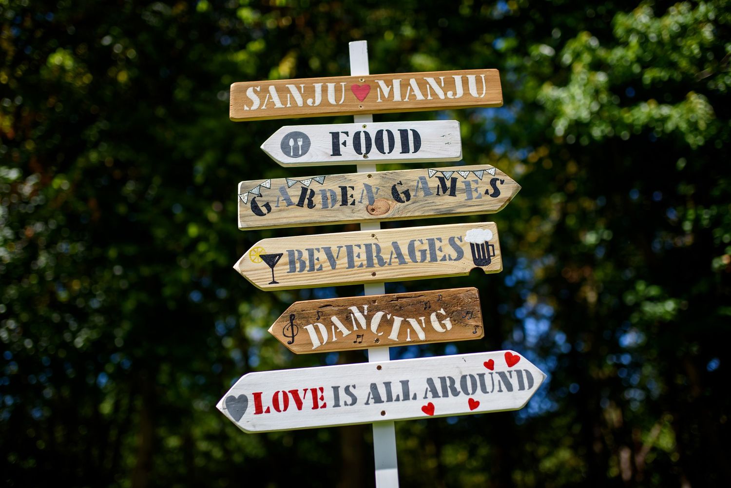 Rustic wooden directional signs point to food, beverages, and dancing at an outdoor event venue.