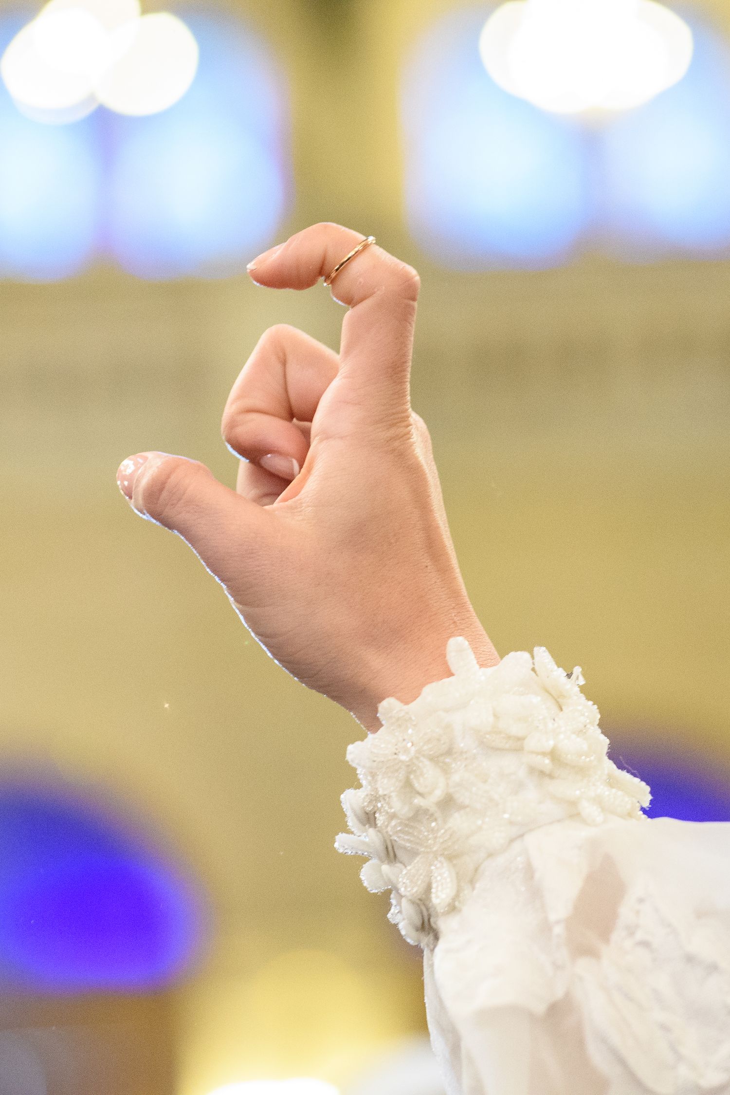 A delicate white lace sleeve detail shown in close-up with blurred bokeh lights in the background.