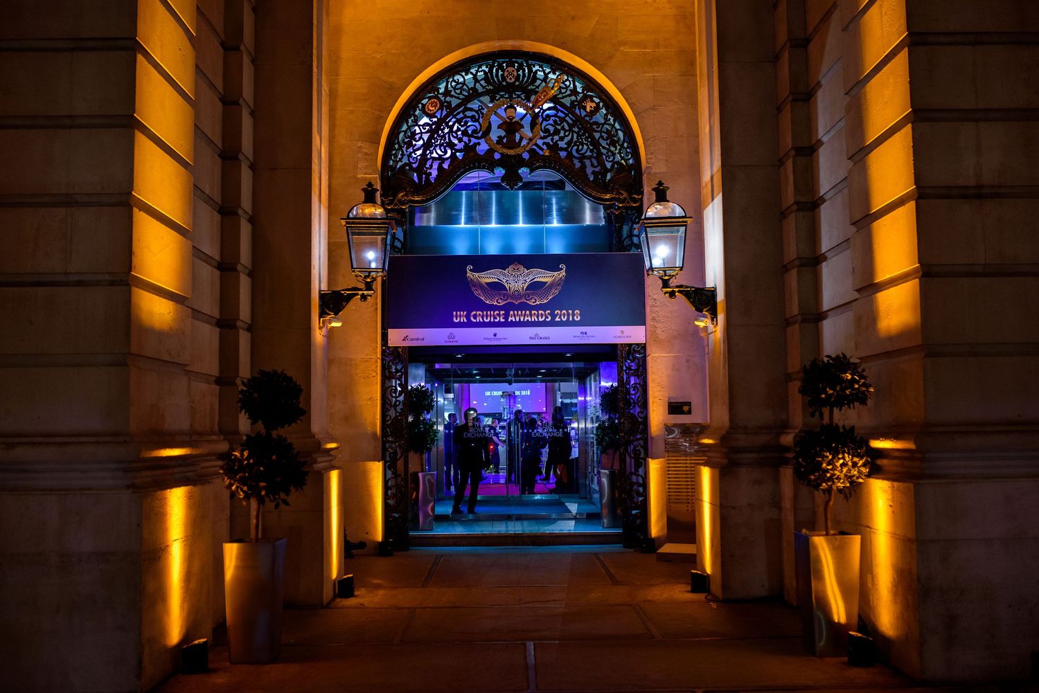 Dramatic archway corridor with amber uplighting and purple accents leading to illuminated entrance.