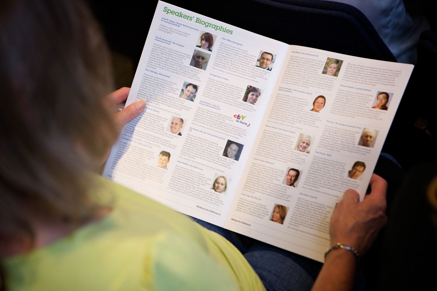 Someone reading through pages of what appears to be a program or event booklet.