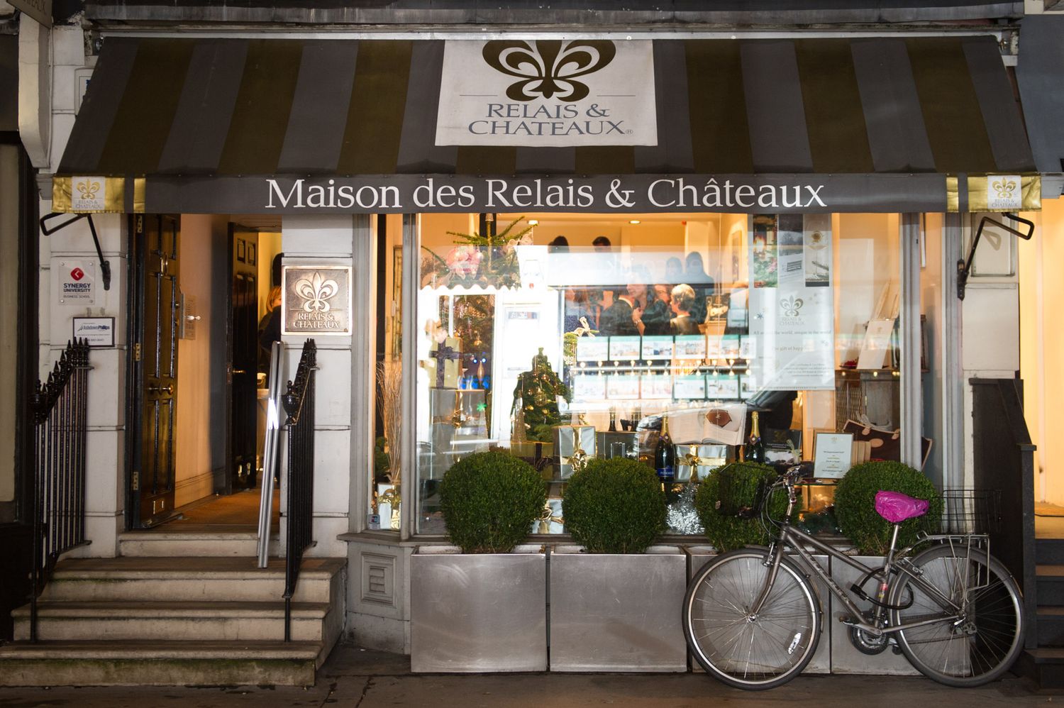 Storefront exterior of a classic French restaurant with awnings and outdoor seating at night.