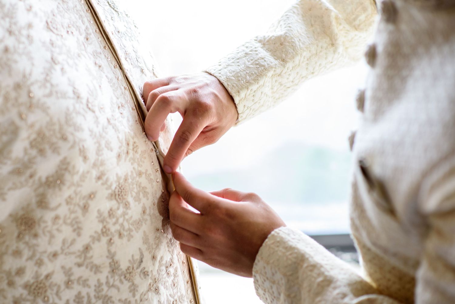 Close up of hands gently adjusting delicate white lace fabric with soft natural lighting.