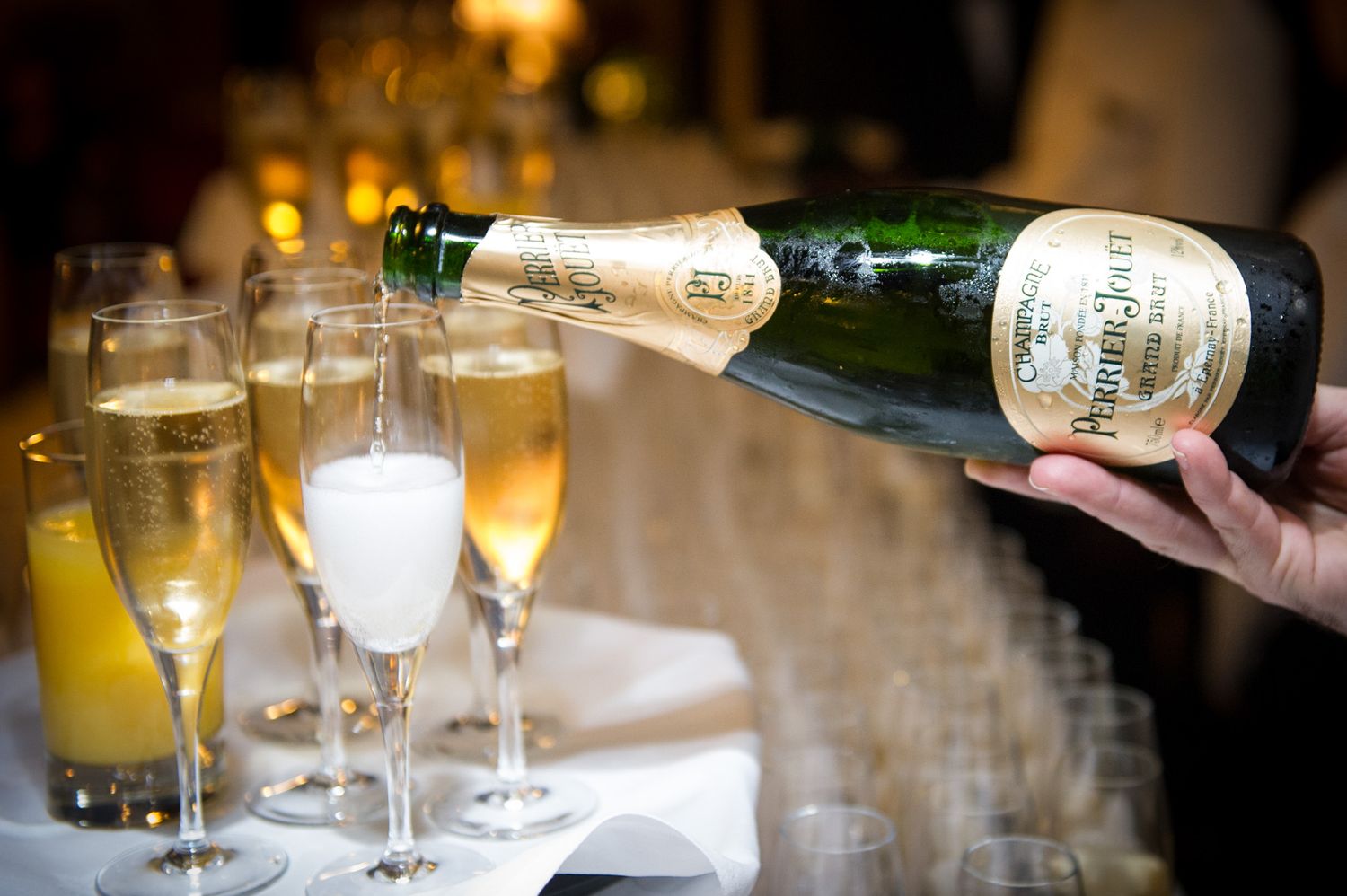 Champagne glasses being served at an upscale event with ambient lighting.