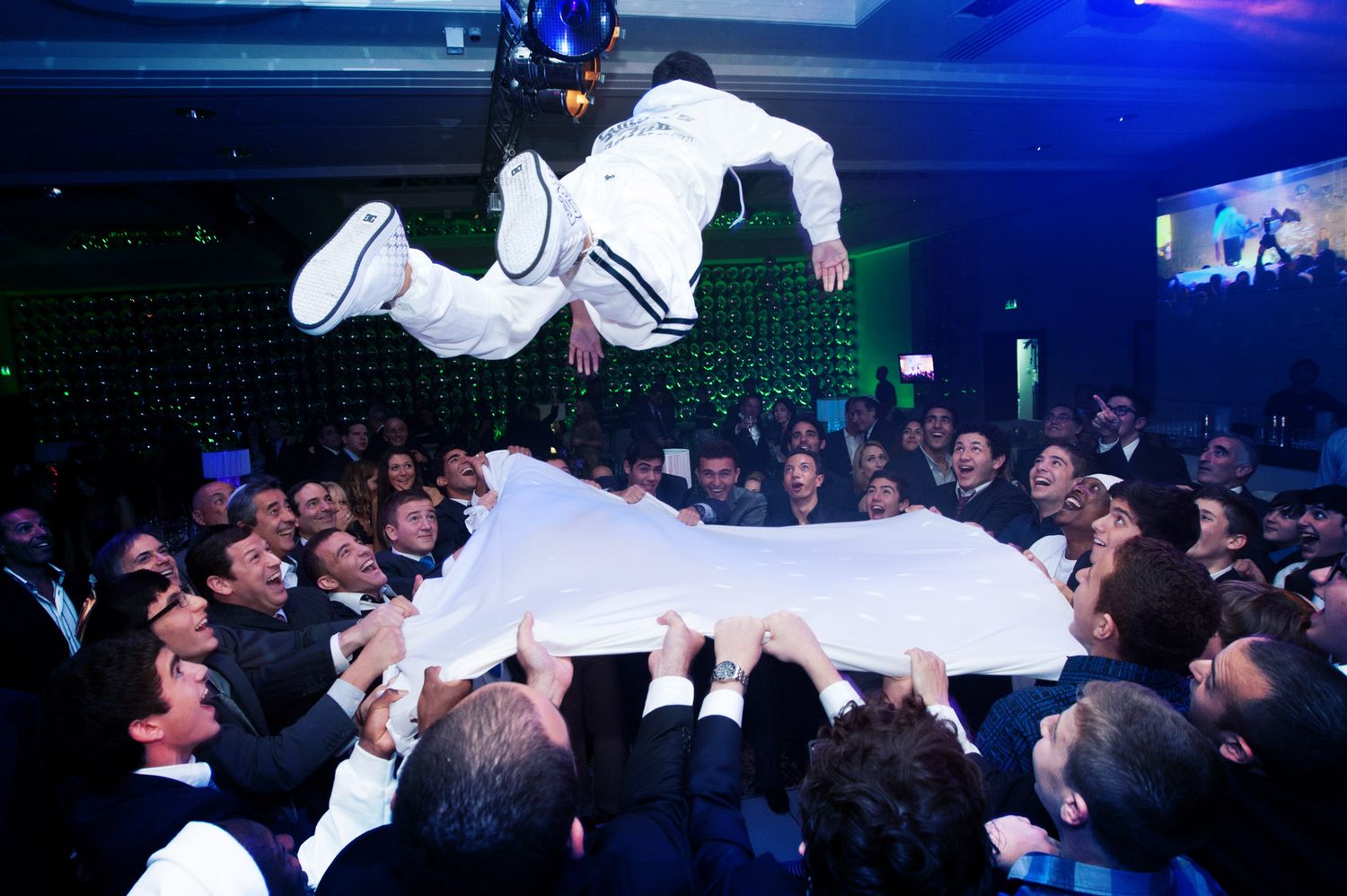 Crowd gathered at a nightclub event with blue lighting and atmospheric effects creating an energetic party atmosphere.