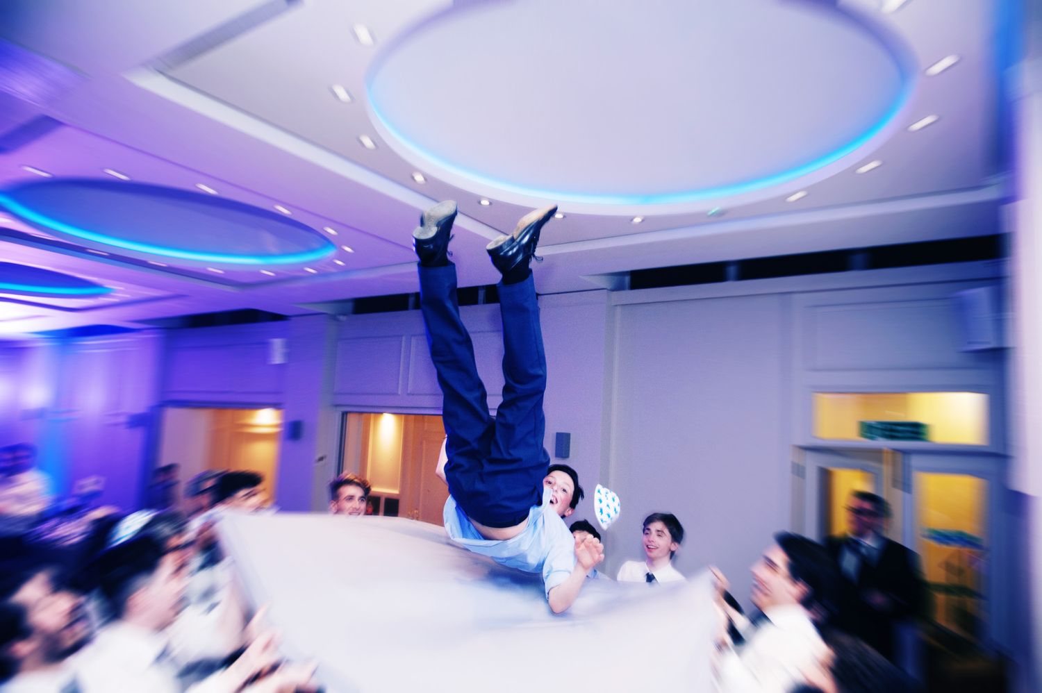 Modern reception venue with blue LED lighting and circular ceiling details during a celebration.