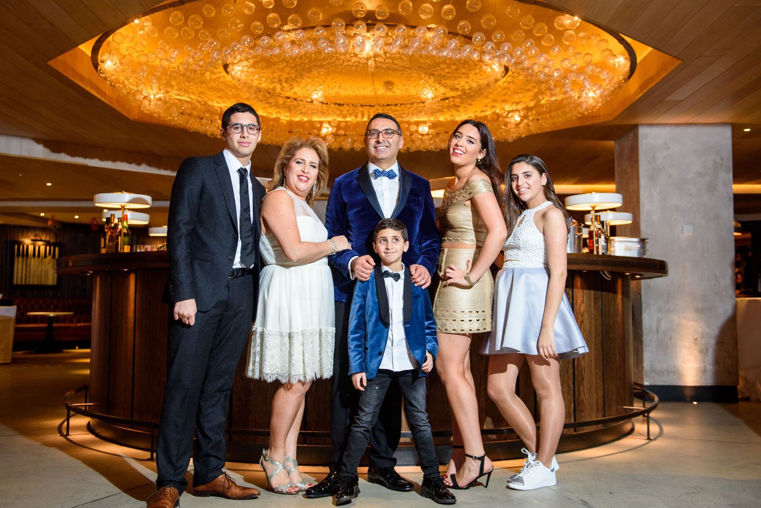 Wedding party poses together in an elegant hotel lobby under warm lighting.