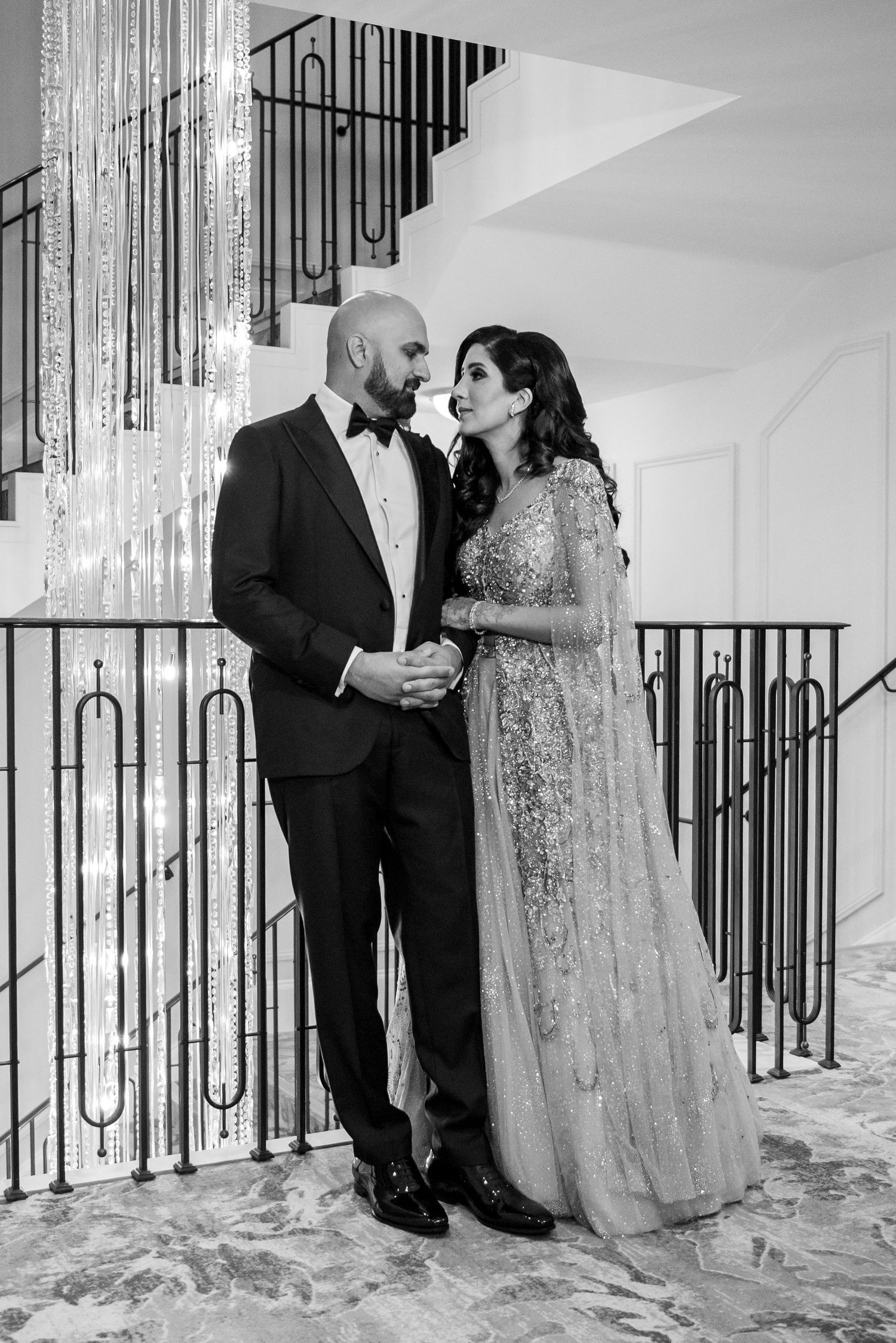 Black and white triptych of a couple sharing intimate moments by an elegant staircase railing at a wedding venue.