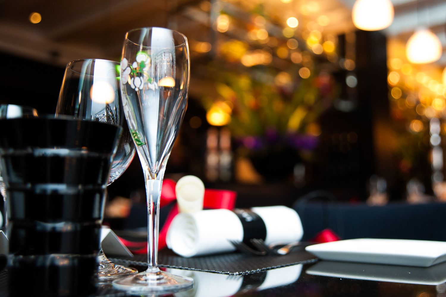 Elegant wine glasses and table settings at an upscale event with warm ambient lighting.