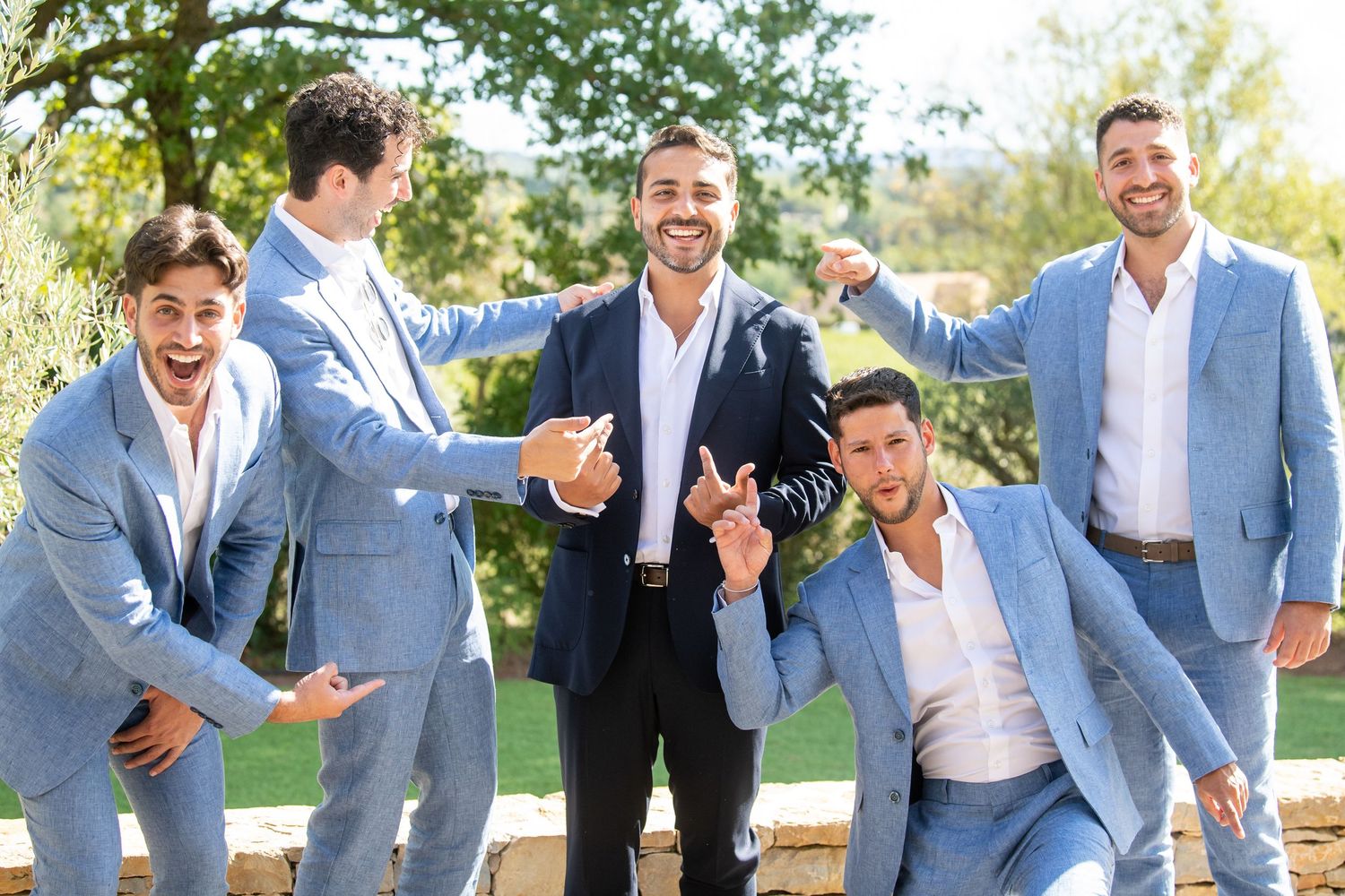 A group in matching light blue suits and white shirts laughing together while walking outdoors.