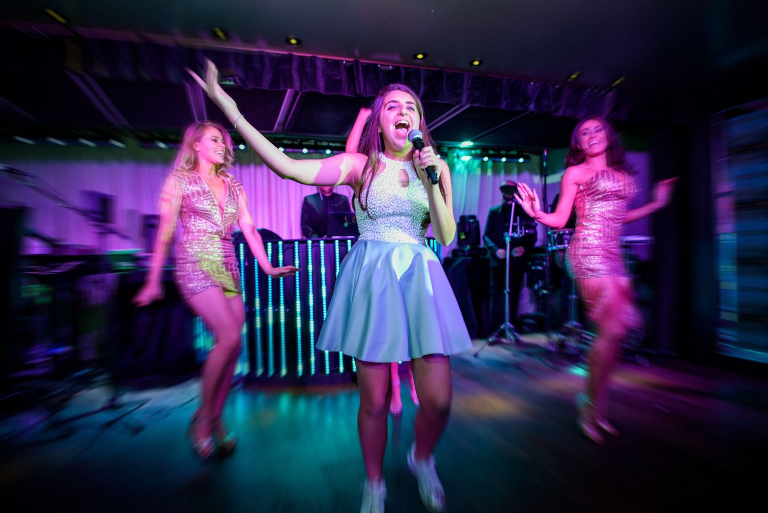 Wedding reception dance party with colorful purple lighting and guests dancing on the dance floor.