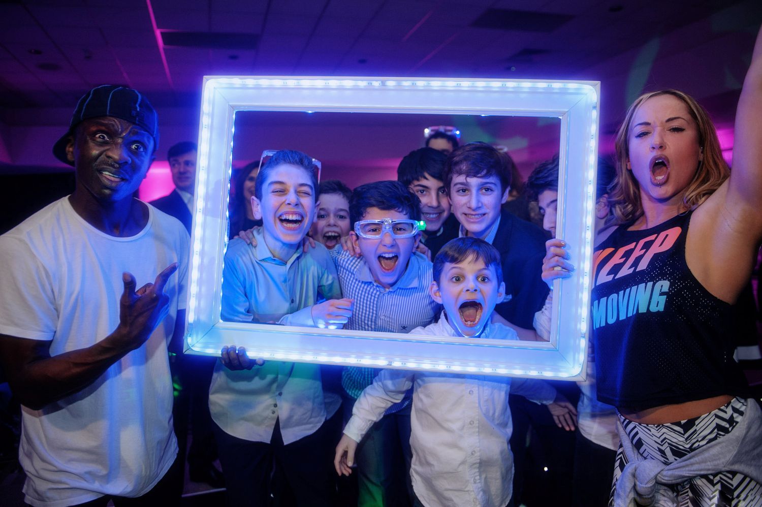 Crowd of excited people at a nightclub event with blue neon lighting and energetic atmosphere.