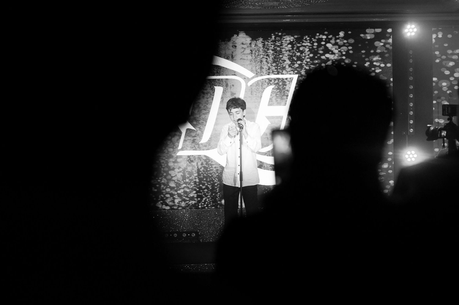 Black and white film strip showing dark silhouettes against bright light sources in a moody nighttime scene.