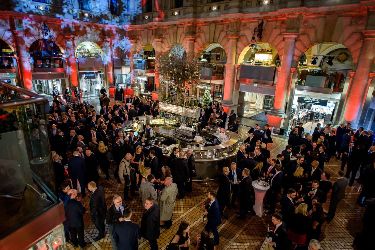 Crowded indoor venue with red accent lighting and architectural details.
