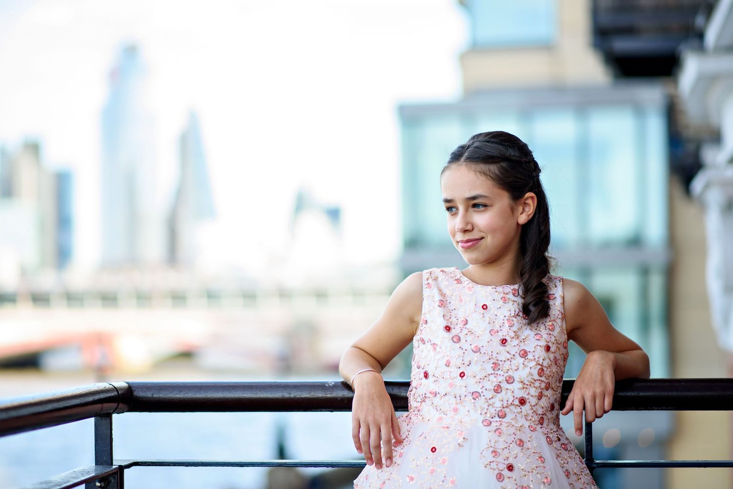 A person in a pink floral dress poses confidently in different positions against an office building backdrop.