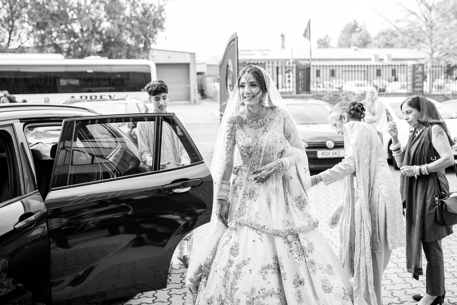 A black and white wedding party exits a church while guests throw rice in celebration.