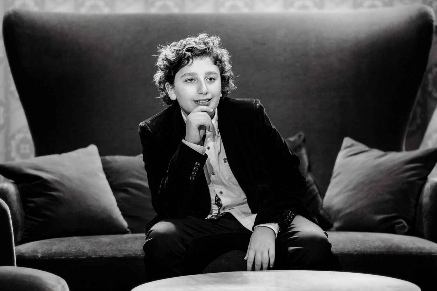 A black and white photo shows a person in a dark jacket reclining on a couch or sofa.