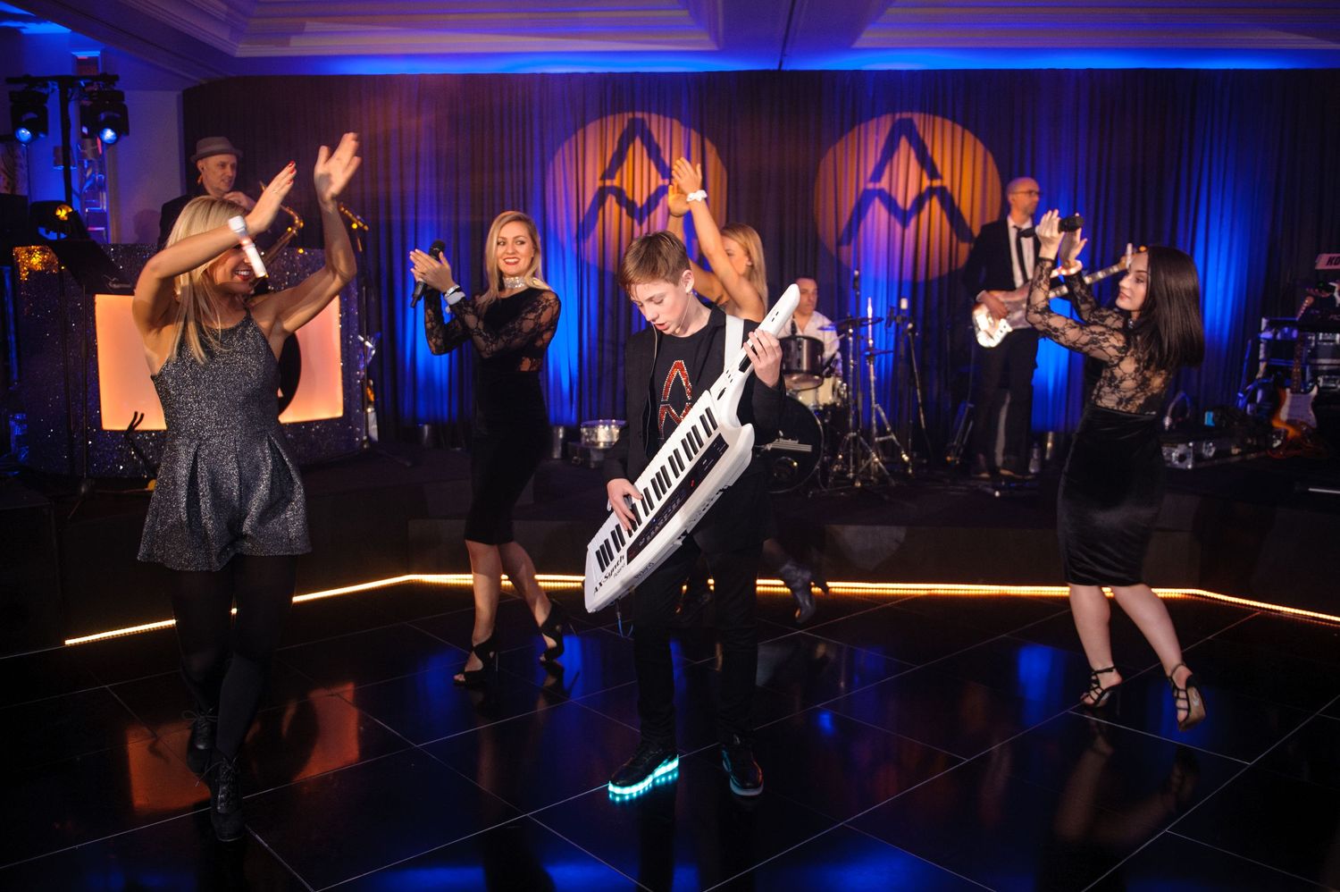 Wedding reception venue with dramatic blue uplighting and entertainment performers on stage.