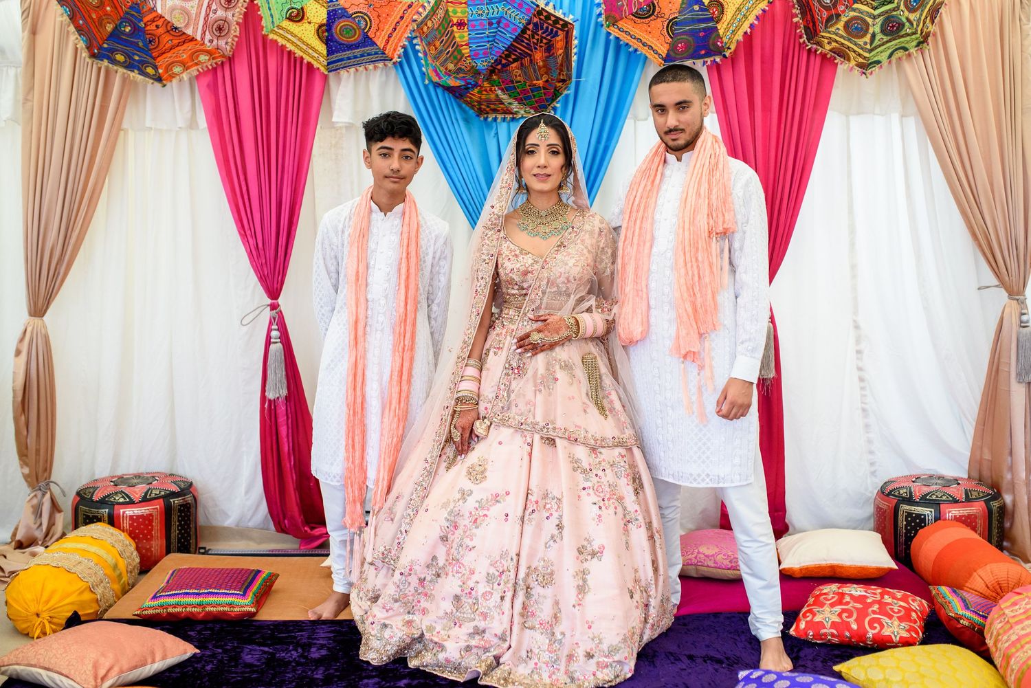 Colorful Indian wedding ceremony setup with pink and beige curtains and decorative elements in traditional style.