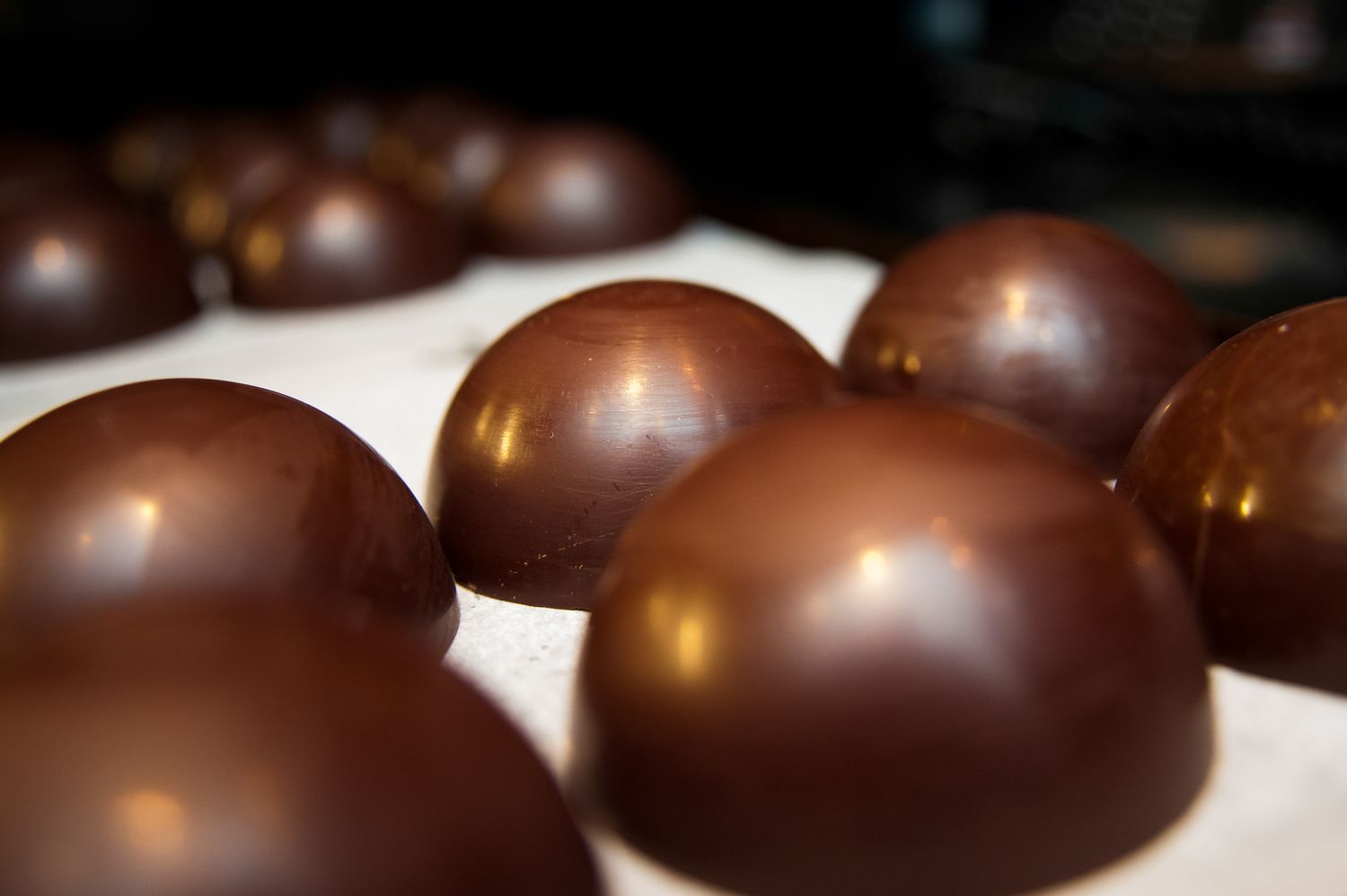 Row of artisanal chocolate truffles displayed on a dark surface.