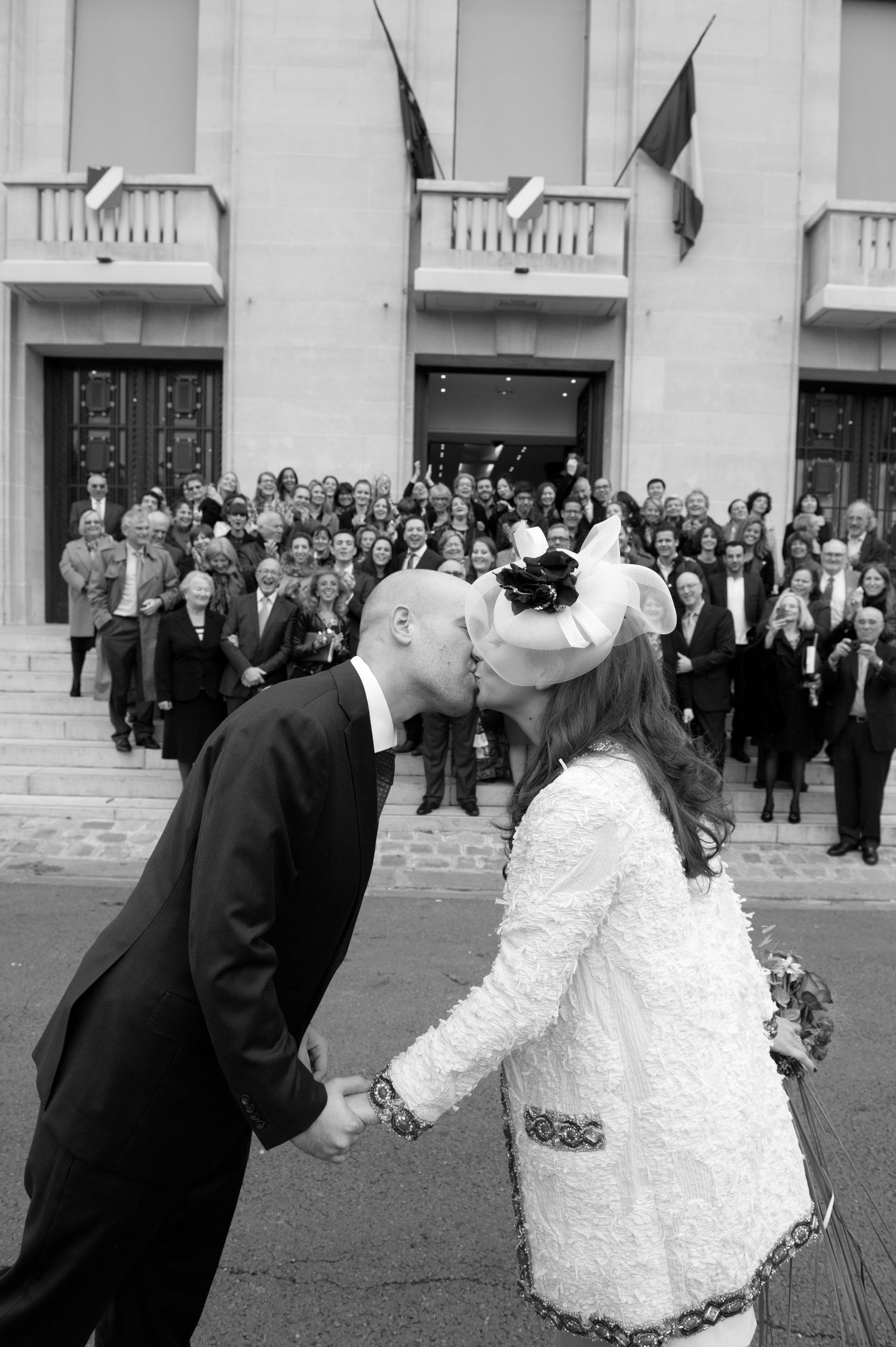 A sequence of black and white wedding photos showing a couple in formal attire sharing a romantic dip pose outside a building.