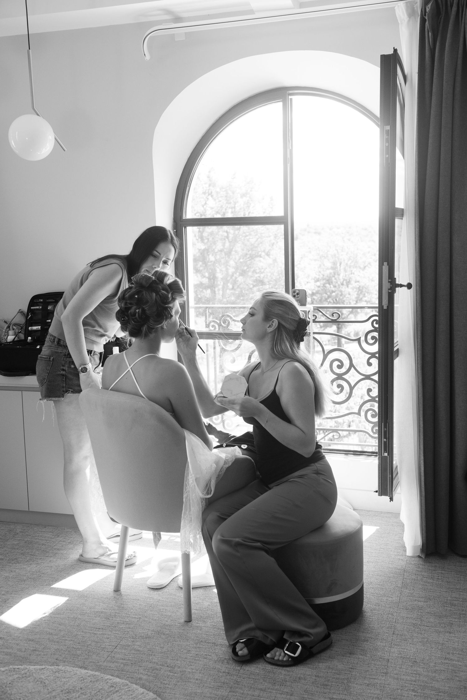 Black and white photo of a quiet morning preparation scene by an arched window with sunlight streaming in.