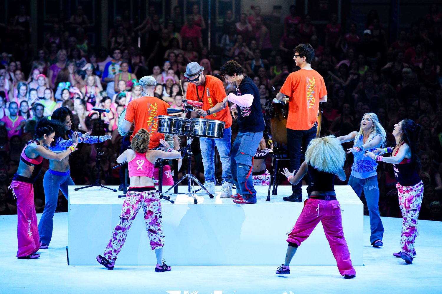 Ice skaters performing choreographed movements on a brightly lit rink.