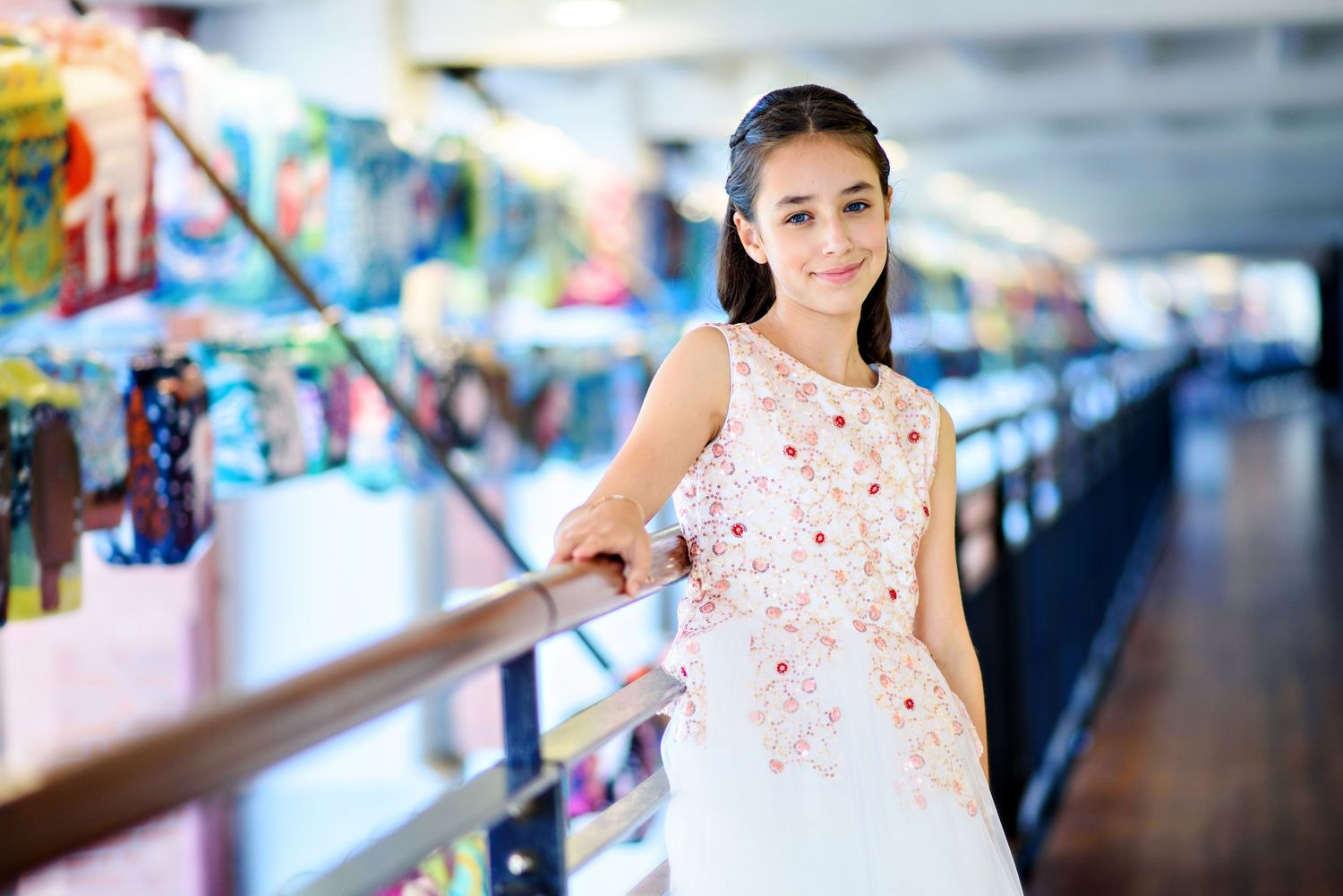 A person in a white and pink polka dot dress poses in front of a blurred shopping center background.