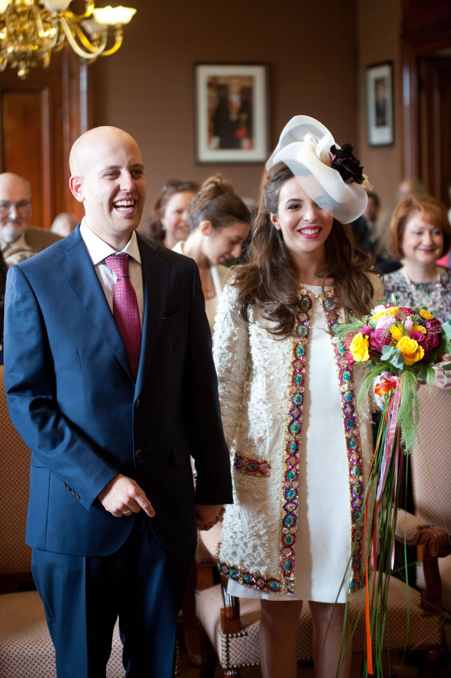 Wedding guests mingle and celebrate during a joyful reception with colorful floral bouquets and formal attire.