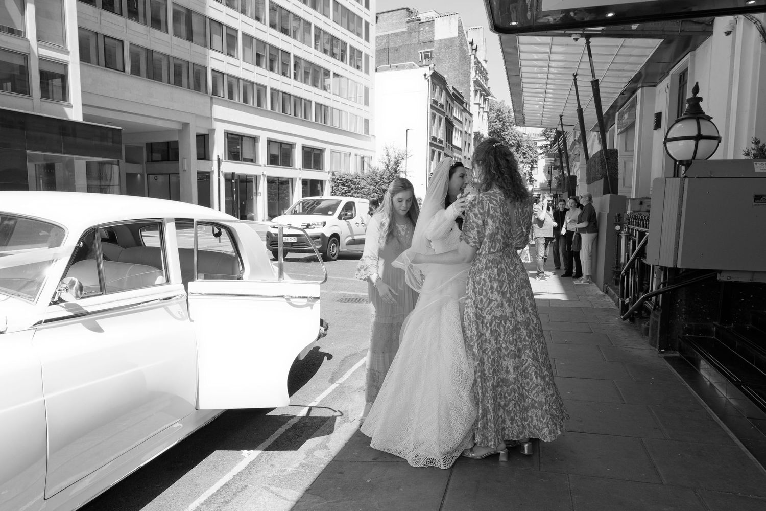 A black and white photo collage showing wedding moments with vintage cars, architecture, and formal attire.