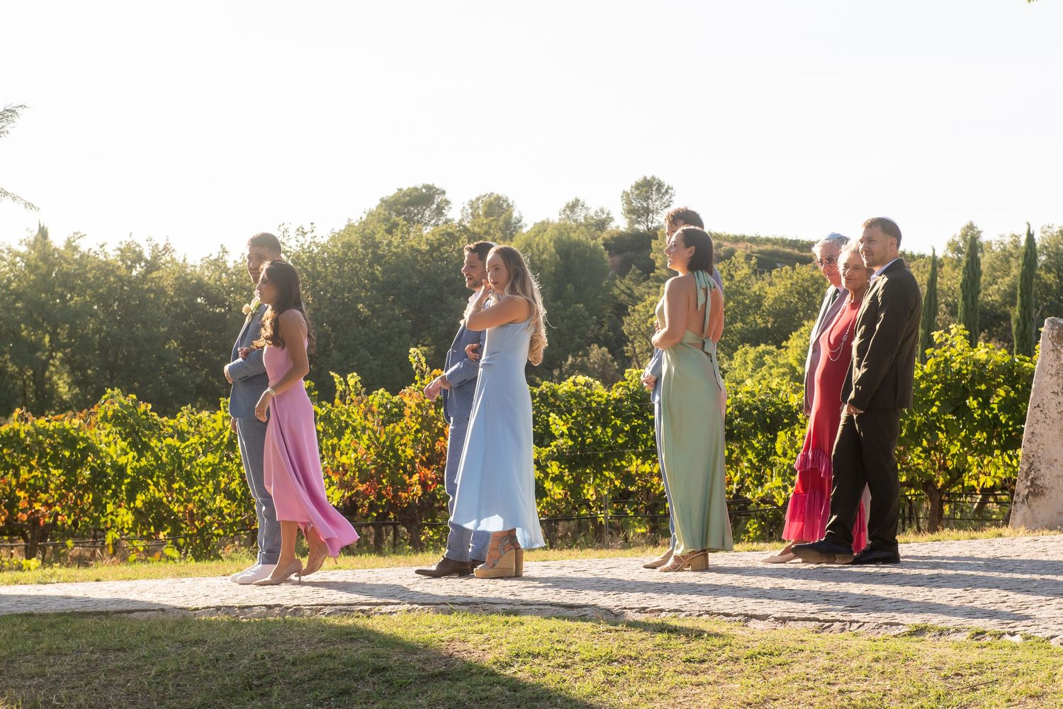 People walking along a path at sunset with sunflowers in a garden setting during golden hour.