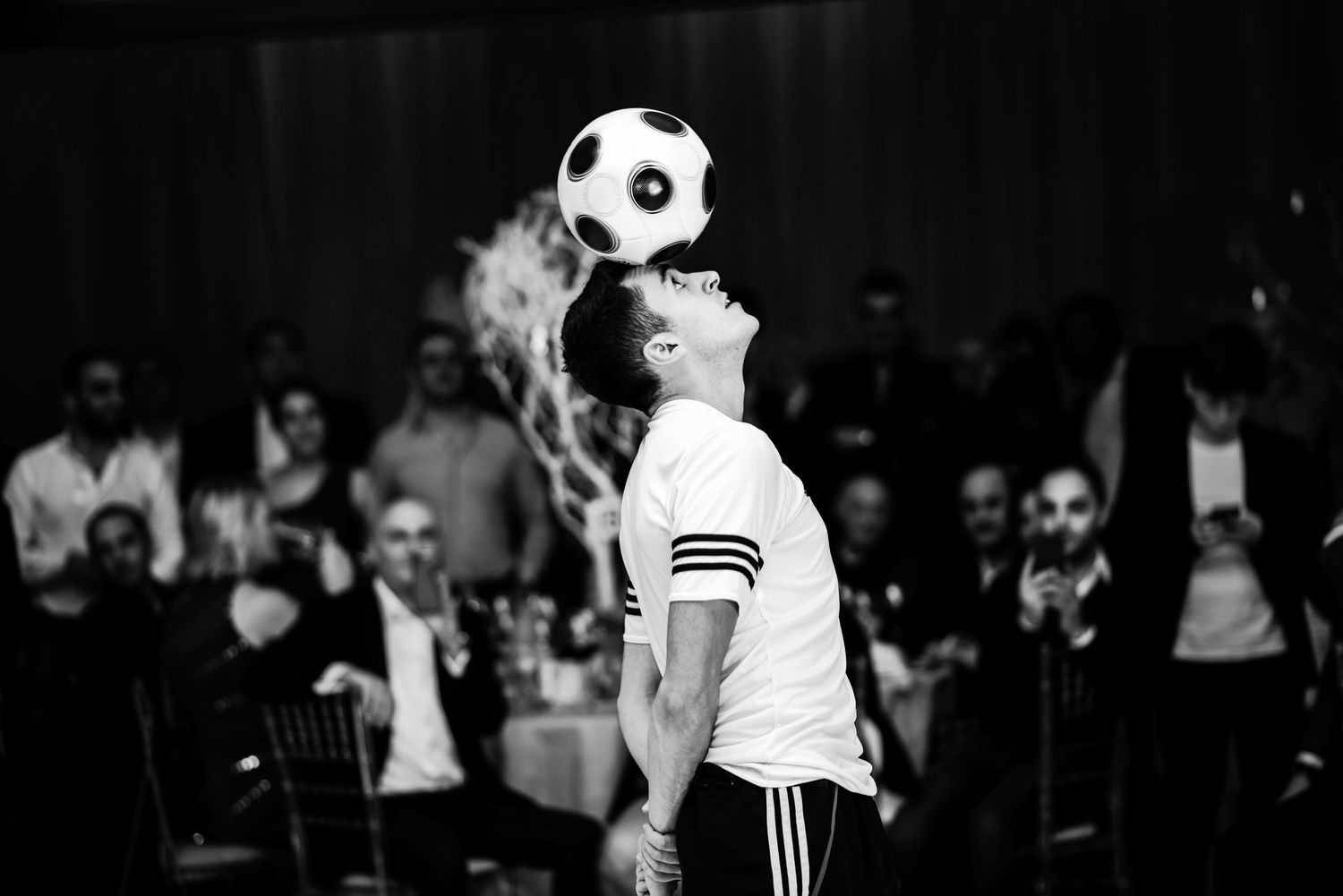 A soccer player in white uniform performs a header with a ball during a nighttime match.