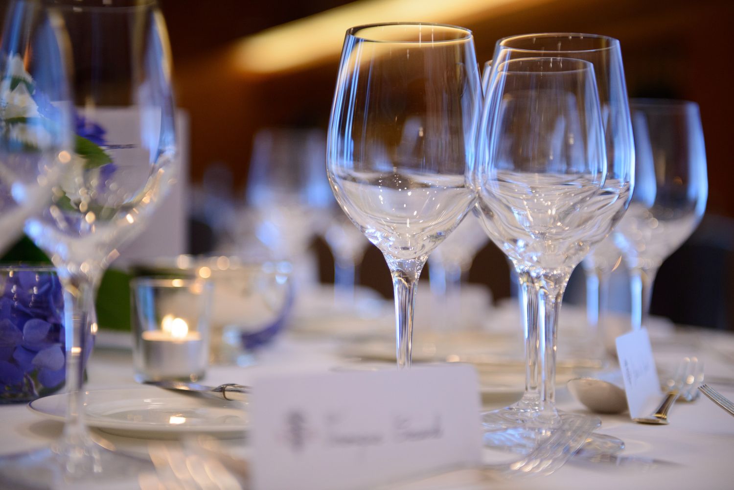 Elegant table settings with wine glasses and place settings in a dimly lit restaurant interior.