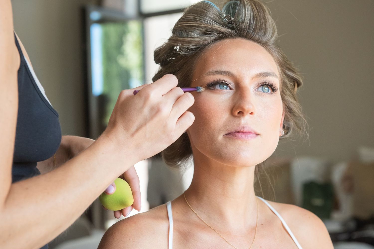 Professional makeup artist applies finishing touches and cosmetics during a bridal preparation session.