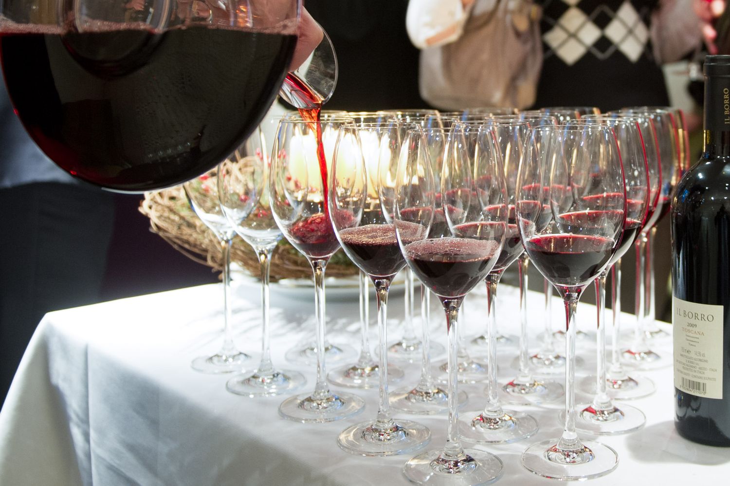 Row of empty wine glasses arranged on a dark table at an upscale event.